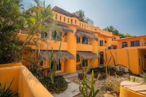 an orange building with palm trees in front of it at Villa Casalet in Puerto Escondido
