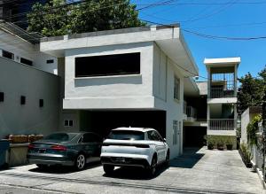 two cars parked in a parking lot in front of a house at LÁZARO D primer piso in Monterrey