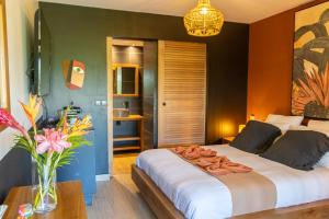 a bedroom with a large bed and a vase of flowers at Village Soleil in Le Gosier