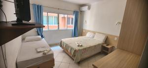 a small room with a bed and a television at Hotel Kolman in Capão da Canoa +78 photos