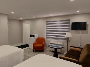 a hotel room with a bed and a chair and a tv at Wiarton Willys Inn in Wiarton