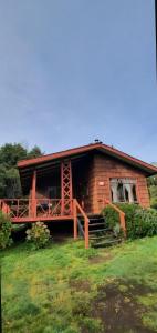 a log cabin with a porch and a house at Cabañas El Nuevo Cimarrón in Puerto Varas