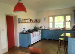 a kitchen with blue cabinets and a red light at College Farm in Brackley