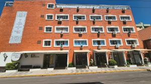 a large red brick building with windows on a street at Hotel Kolman in Capão da Canoa