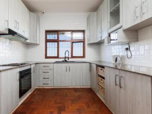 a kitchen with white cabinets and a wooden floor at La Vue in Port Shepstone