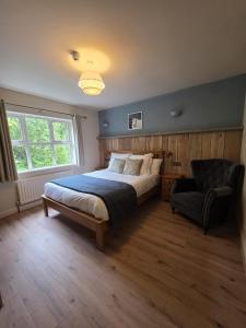 a bedroom with a large bed and a chair at Connemara National Park Lodge in Letterfrack