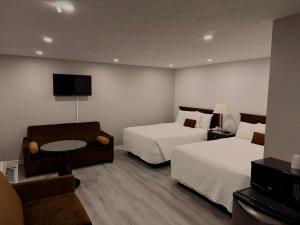 a hotel room with two beds and a couch at Wiarton Willys Inn in Wiarton