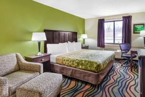 a hotel room with a bed and a chair at Econo Lodge Inn & Suites Oconto in Oconto +24 photos