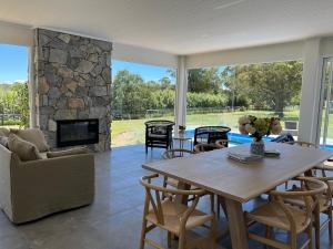 a living room with a table and a stone fireplace at Kalamunda Estate with Pool, Fire Pit & BBQ Deck in Bundanoon