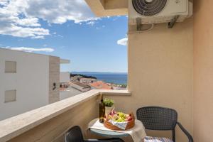 a balcony with a table and chairs and a view of the ocean at Apartmani Putnik in Baška Voda