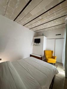 a bedroom with a bed and a yellow chair at Marta House 2 in Trapani
