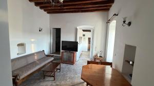 a living room with a couch and a flat screen tv at Camaraki Hill House Serifos in Serifos Chora