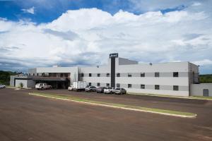 un grande edificio bianco con auto parcheggiate in un parcheggio di Ives Hotel a Costa Rica