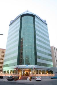 un gran edificio de cristal con coches estacionados frente a él en Sara Plaza, en Kuwait