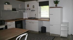 a kitchen with white cabinets and a table and a window at Ferienwohnung Hexenhäusla in Gößweinstein