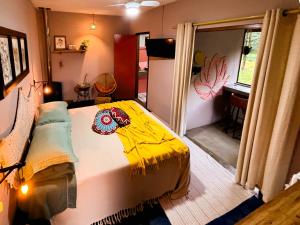 a bedroom with a bed with a yellow blanket on it at Sítio Passarim in São Francisco Xavier