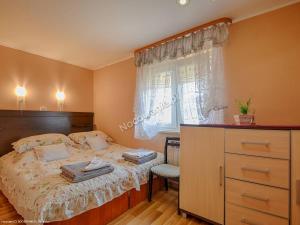 a bedroom with a bed with a dresser and a window at Agroturystyka U Marty in Trzcinica