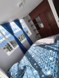 a bedroom with a bed and two windows at Brisas del Santander in Fusagasuga +1 photo