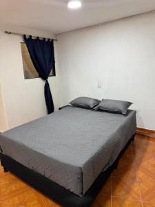 a bed in a bedroom with a blue curtain at Casa del parque in Bello +6 photos