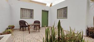 a patio with two chairs and a table in front of a building at Petit villa centre harhoura Près de la plage in Temara