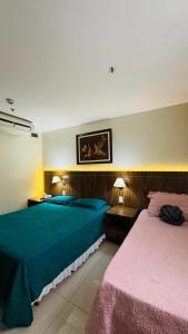 a bedroom with two beds and two tables with lamps at Quarto Mobiliado no Hotel Go Inn Taguatinga com Wi-Fi, Ar Condicionado e Estacionamento Grátis in Brasília +24 photos