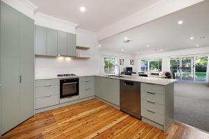 a large kitchen with white cabinets and a wooden floor at Delightful Digs on David in Albury