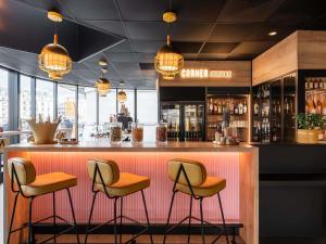 a bar with three stools at a bar with lights at Mercure Paris Gare De Lyon TGV in Paris