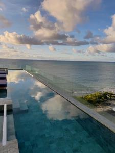 a swimming pool with a view of the ocean at New Time 304 Maceió Alagoas in Maceió