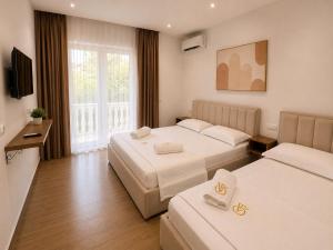 a hotel room with two beds and a television at Vila Beqja in Durrës