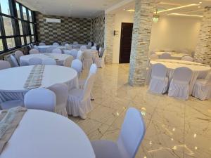 a banquet hall with white tables and white chairs at Hotel Al Abraj in Oran