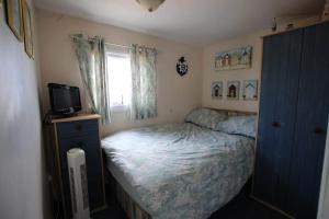 a small bedroom with a bed and a television at Sheppey Village Ollie in Leysdown-on-Sea