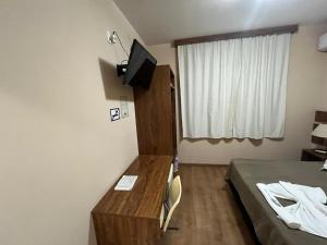 a bedroom with a desk and a bed and a television at Hotel Casimiro in Ponta Grossa