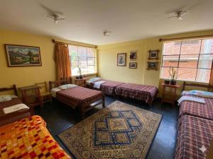 a room with three beds and a rug at CAYESH Guest House in Huaraz