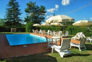 eine Gruppe von Stühlen und Sonnenschirmen neben einem Pool in der Unterkunft Villa Marisel in Gricignano