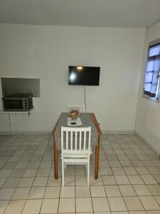 a dining room table with a white chair and a microwave at Paradies Caraïbes I in Les Abymes