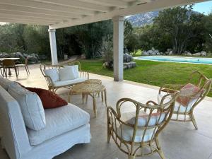 a patio with a couch and chairs and a pool at Exclusive Villa Aurea with private pool in Cugnana