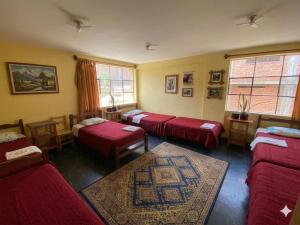 a room with four beds and a rug at CAYESH Guest House in Huaraz