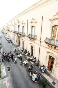un grupo de personas sentadas en mesas fuera de un edificio en Pepè Concetta e la movida en Noto