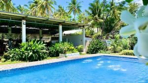 a pool in front of a house with palm trees at Alzurich Private Resort in Dauin