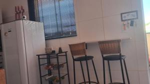 a kitchen with two bar stools and a refrigerator at Vivendas Raízes do forte in Praia do Forte +1 photo