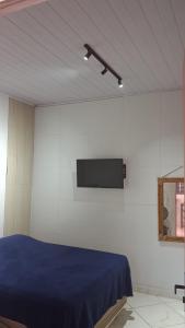 a room with a bed and a tv on a wall at Vivendas Raízes do forte in Praia do Forte
