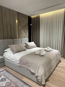 a bedroom with a large bed with white sheets and pillows at Modern Lake Apartment Tirana - Quiet Stay near Liqeni i Thatë in Tirana