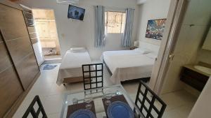 a small room with two beds and a glass table at 10 Studios in São Paulo