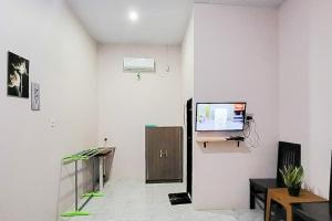 a living room with a tv on a white wall at RedDoorz at Morowali Sulawesi Tengah in Ulunipa