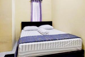 a bed with two pillows and a blue curtain at RedDoorz at Morowali Sulawesi Tengah in Ulunipa
