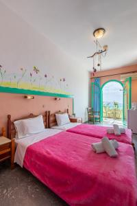 two beds in a room with a red blanket at Erofili Rooms in Agia Galini