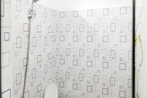 a bathroom with a white wall with a shower at RedDoorz at Morowali Sulawesi Tengah in Ulunipa