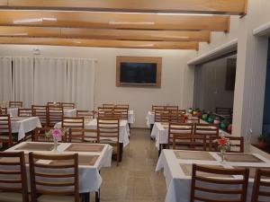 a dining room with tables and chairs and a television at Priamo Hotel in Santo Antonio do Sudoeste