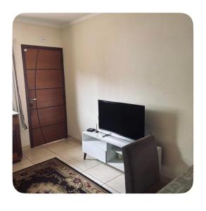 a living room with a flat screen tv and a chair at Raquel in Londrina
