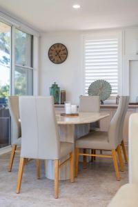 a dining room table and chairs with a clock on the wall at Beach Street Oasis - Tuncurry in Tuncurry